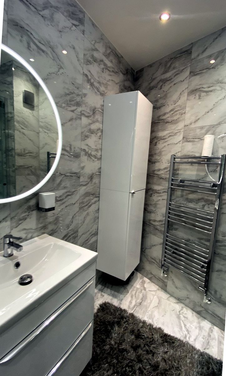 Marble bathroom fit-out with illuminated mirror and chrome heated towel rail