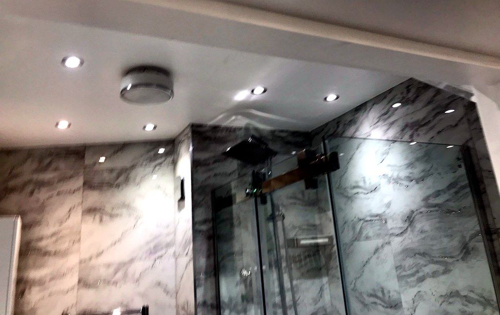 Bathroom detail — marble tiling, glass shower screen and rain shower head